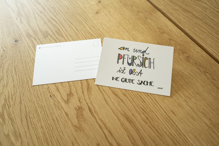 weiße Postkarte mit bunter Schrift "an und Pfürsich ist Obst ne gute Sache"